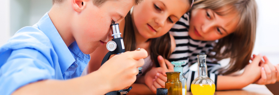 three students looking through a microscope